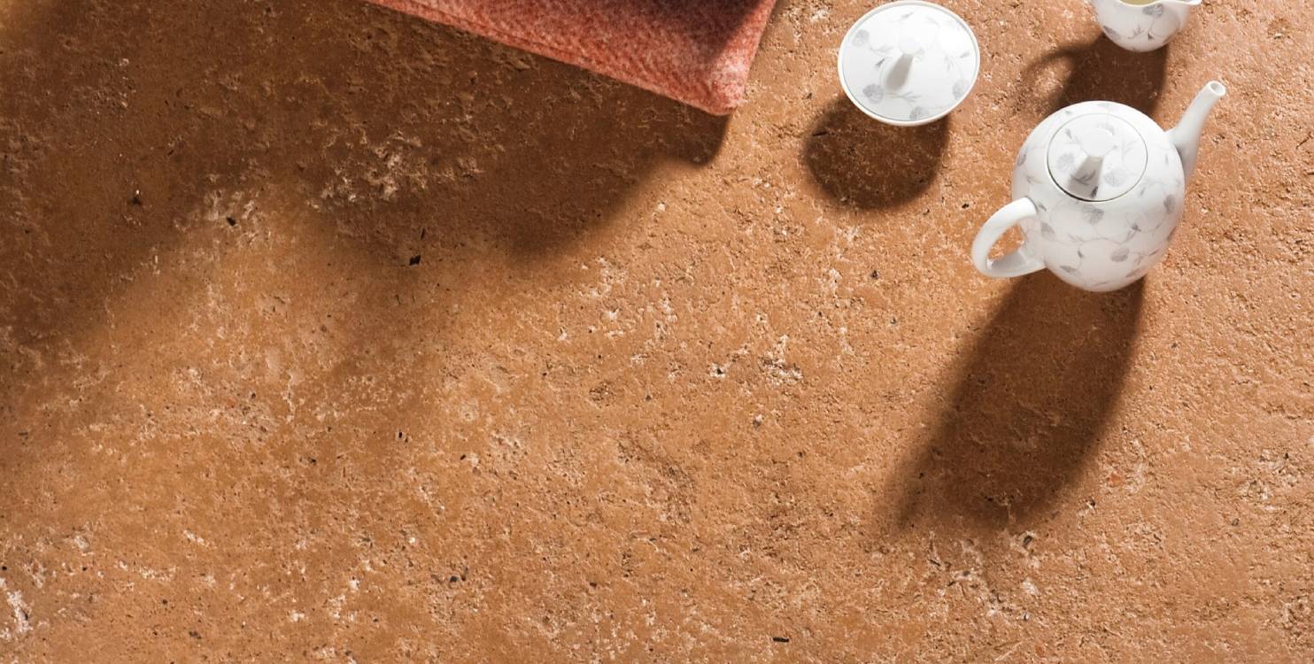 Natürlicher Stampflehmboden mit Teppich und Teegeschirr
